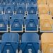 Uniform rows of red, blue, and yellow stadium seats with numbers visible.