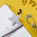 Flat lay of a notebook with motivational text, trophy, and star confetti on a yellow background.